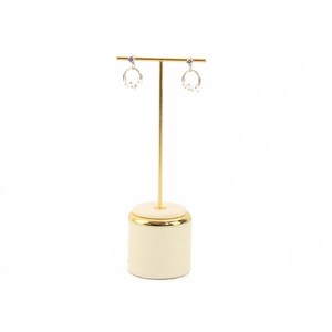 Detail of elegant gold hoop earrings with white pearls on a minimalist T-bar metal stand