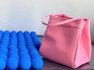 Dettaglio della borsa a secchiello in pelle PU rosa con trama martellata e manico morbido
