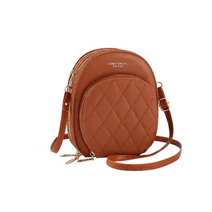 Detail of caramel PU leather crossbody bag with diamond quilting and gold hardware