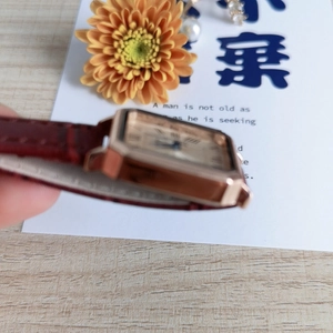 Detail view of square rose gold watch with red leather crocodile strap and Roman numerals