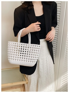 Detailed view of a white woven hollow-out basket bag held by a model for beach vacation