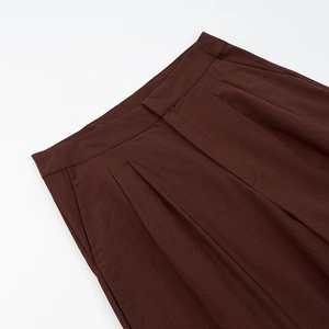 Gros plan détaillé de la taille plissée et du zip sur le pantalon marron en lin