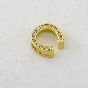Macro shot of horseshoe-shaped golden ear clip with micro-paved sparkling cubic zirconia