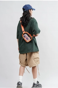 Rear view of transparent PVC crossbody bag with orange straps on a model in a studio