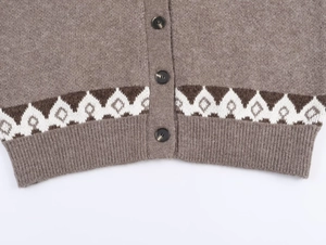 Detail of brown jacquard knit cardigan featuring resin buttons and ribbed hem texture