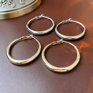 Detailed view of polished gold and silver hoop earrings on a textured dark brown surface