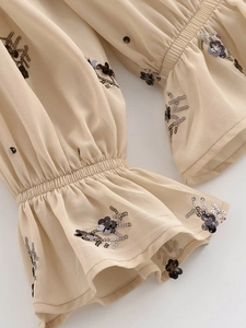 Détail des poignets élastiques à volants sur chemisier en mousseline beige à paillettes
