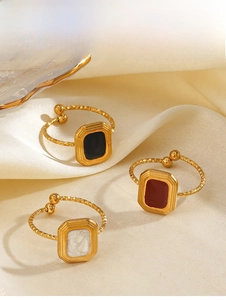 Macro shot of geometric square rings with black, red, and white enamel on gold bands