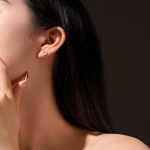 Macro shot of V-shaped gold stud earrings with clear zircon stones on a model ear