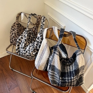 Detail of plush faux fur tote bags in leopard and checkered patterns on an acrylic chair