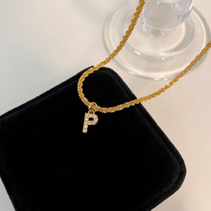 Détail du pendentif lettre P doré serti de zircons sur un coffret en velours noir