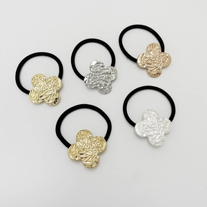 Close-up of five elastic hair ties featuring textured gold and silver clover metal charms