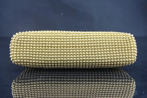 Detail einer goldenen geflochtenen Abendclutch mit aufwendiger Metallperlen-Textur und Glanz