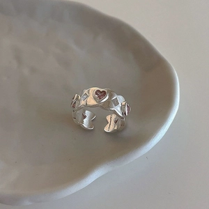 Detailed macro view of silver wavy ring with pink heart stone and zirconia accents
