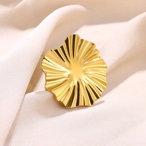 Detailed close-up of golden wavy lava texture ring on minimalist fabric background