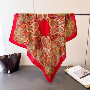 Detailed close-up of a large red silk square scarf with vibrant paisley print patterns