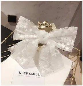 Detail of white oversized lace bow hair clip with floral embroidery on an elegant display
