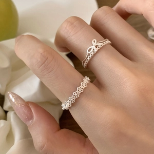 Elegant silver open rings with bow and lace textures on female model fingers