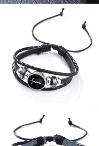 Close-up of black braided leather multi-layer bracelet with faith pendant and metal beads