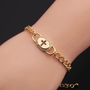 Detail of gold Cuban chain bracelet with a red cubic zirconia cross oval pendant