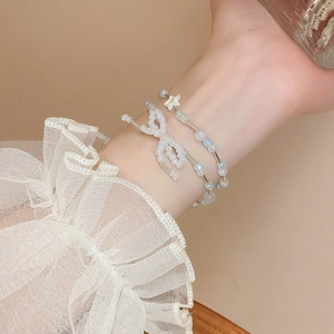 Close-up of double-layer beaded bracelet with bow and star charms on model's wrist