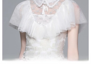 Détail de la robe blanche avec col brodé en dentelle et cape en tulle élégante