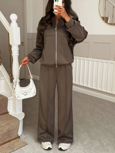 Detailed view of women brown zip-up hoodie and wide-leg knit trousers on a staircase