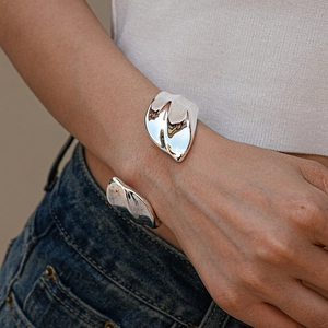 Close-up of a minimalist silver irregular geometric cuff bracelet with mirror-polished finish