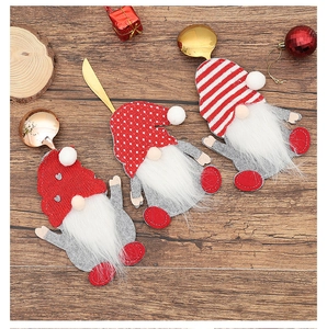 Three gnome Christmas cutlery holders on wooden table with red festive ornaments