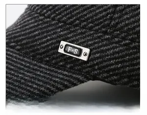 Detalle de la textura de sarga gris oscuro y el emblema metálico en la gorra de invierno