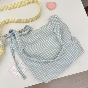 Detail of blue and white checkered canvas tote bag with decorative side ribbon bow
