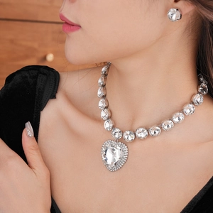 Close-up of luxury silver heart pendant necklace and matching diamond studs on a model