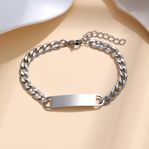 Close-up of a silver stainless steel Cuban link bracelet with a blank rectangular nameplate
