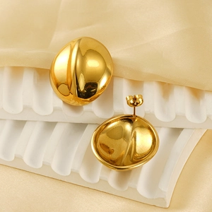 Macro detail of glossy 18k gold plated stainless steel bean earrings on silk background