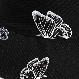 Détail macro d'un imprimé papillon blanc en demi-teintes sur chapeau en sergé noir
