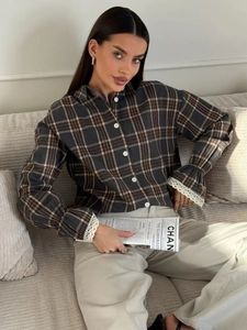 Detail of dark grey plaid shirt sleeve featuring elegant white lace cuffs and pleats