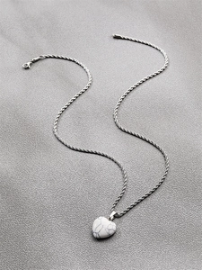 Détail d'un pendentif cœur en marbre blanc avec chaîne torsadée argentée et fermoir