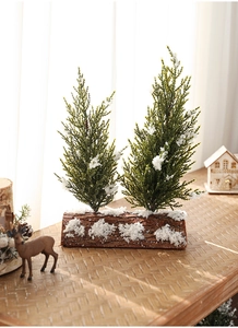 Close-up of dual mini frosted Christmas trees on a rustic log base with realistic fake snow
