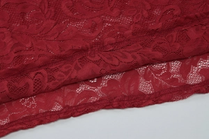 Close-up of red lace fabric showing fine mesh patterns and high-quality stitching details