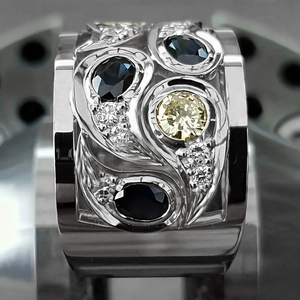 Vue macro d'une bague large en argent avec pierres jaunes et bleues et gravures fluides