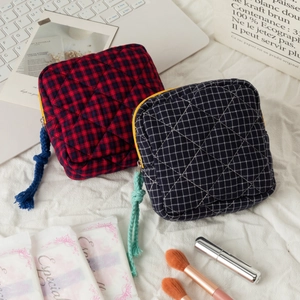 Detail of quilted cotton cosmetic bags with checkered pattern and long knot zipper pulls