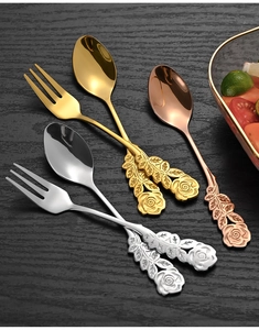 Artistic detail of stainless steel rose engraved spoons and forks in gold, silver, and rose gold