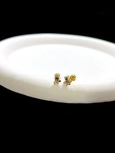Detailed view of small gold-plated flower stud earrings with white enamel petals on a tray
