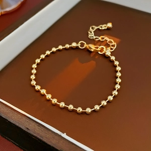 Close-up of a minimalist golden beaded bracelet with lobster clasp and adjustable chain