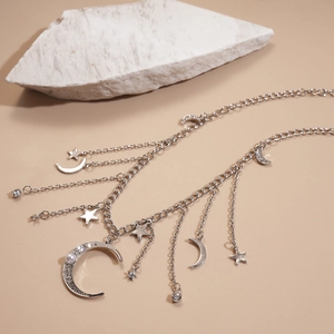 Gros plan de collier argenté avec pendentifs lune, étoiles, strass et perles