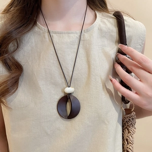 Detail of vintage resin circle pendant on brown wax cord necklace worn by model