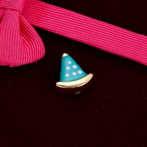 Macro shot of a blue polka dot hat charm with gold brim on red velvet background