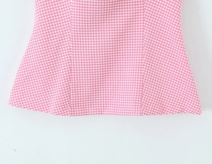 Close-up of pink and white gingham pattern and stitching detail on women's halter top