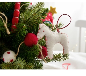 Detail of handmade wool felt Christmas tree ornaments featuring a red and white horse
