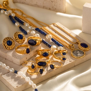 Vintage gold jewelry set with lapis lazuli, pearls and coin pendants on beige travertine